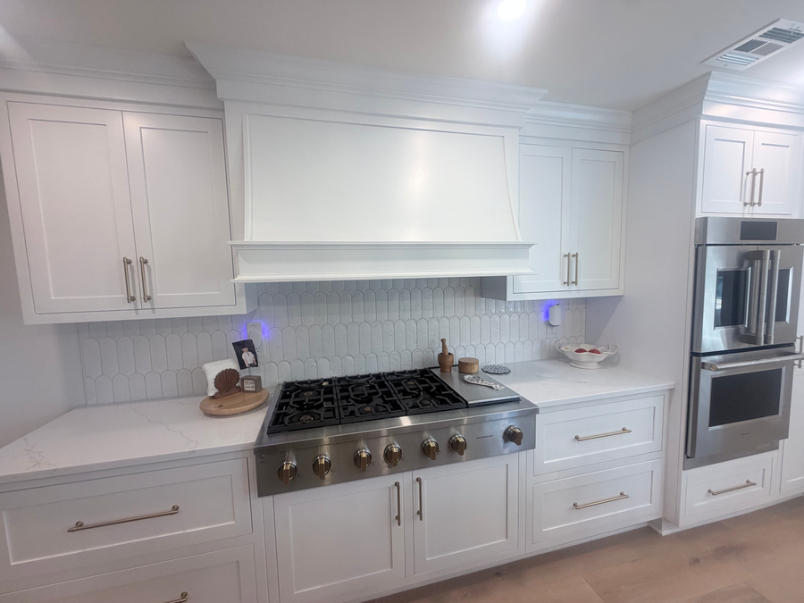 Gas rangetop under a custom hood, with stacked wall ovens