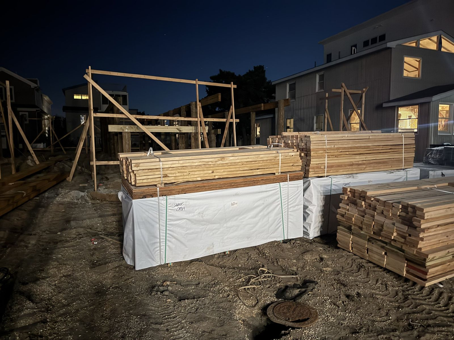 Framing lumber staged on site beside the pilings