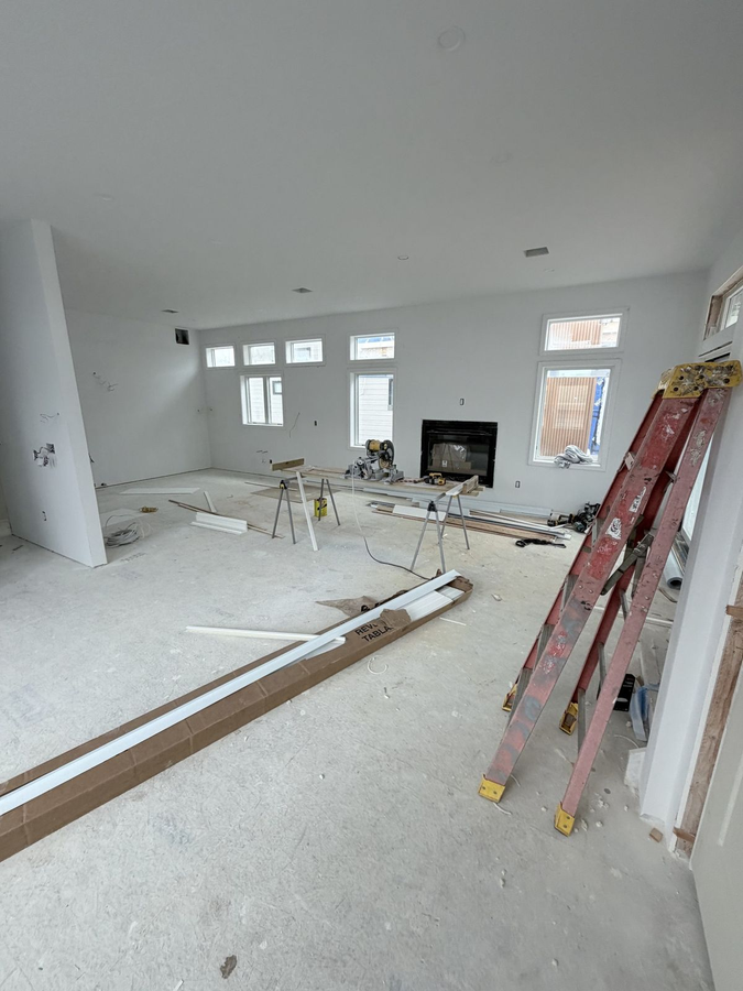 Living room with fireplace wall and tall windows, finishes underway