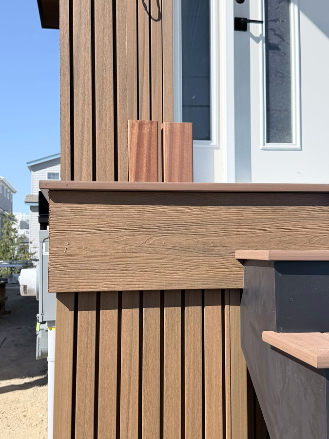Vertical composite slat siding with trim, mahogany posts and an entry door