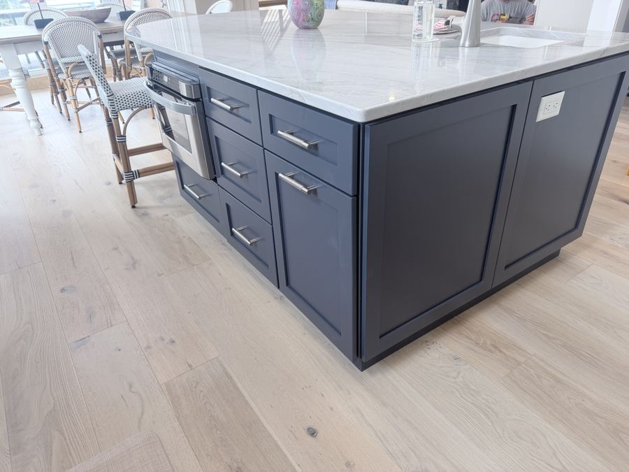 Dark island cabinetry and light wood flooring
