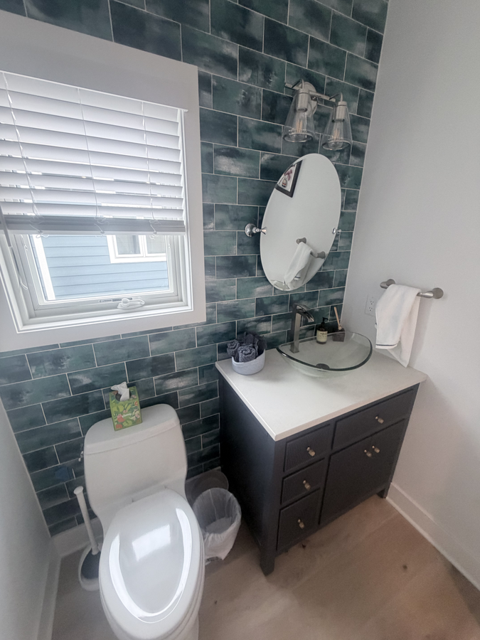 Powder room with a tile accent wall and a dark vanity
